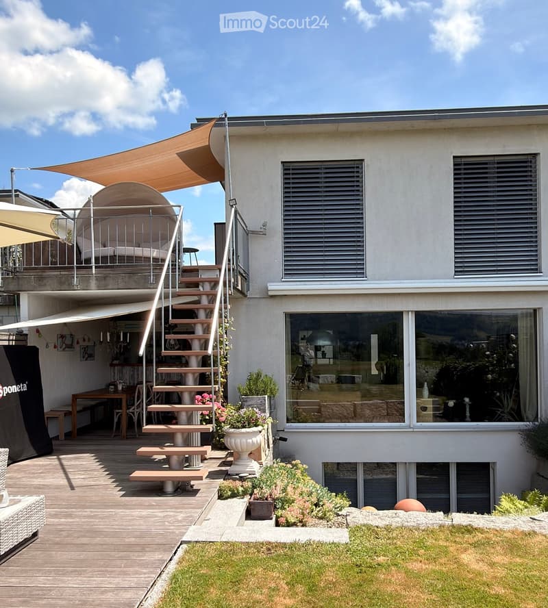 Modern outdoor area with wooden deck, spiral staircase, patio furniture, potted plants, and a covered seating area with a canopy.