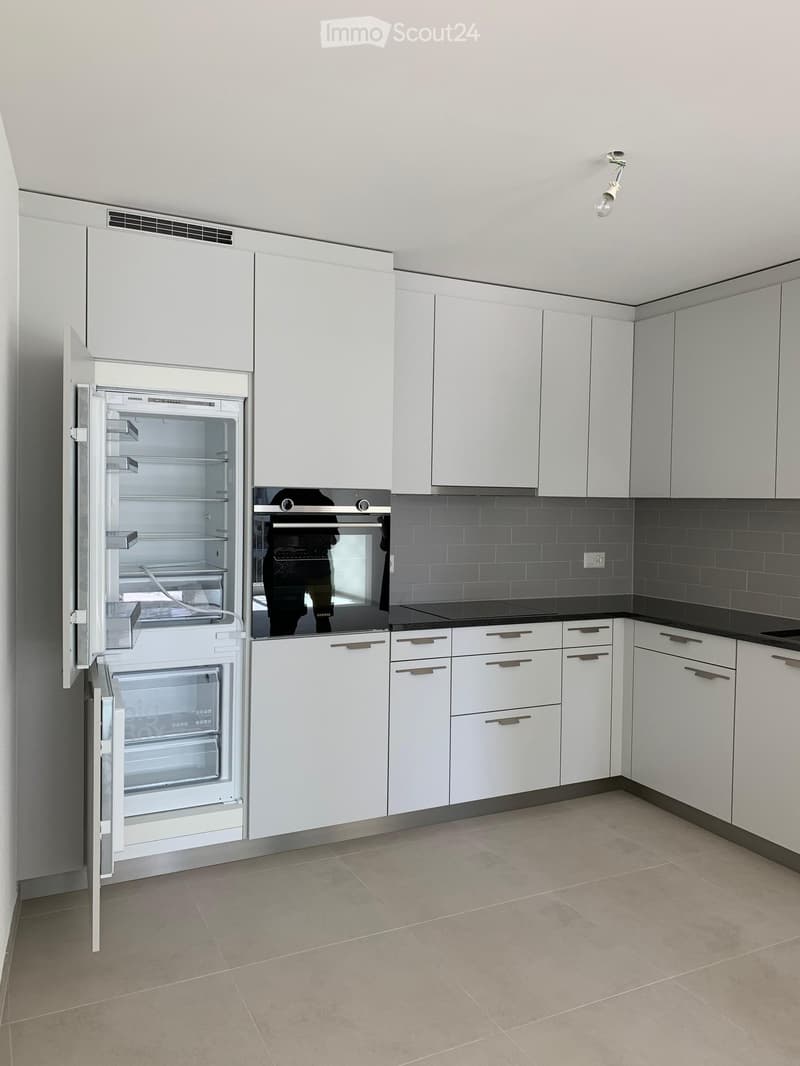 Modern kitchen with white cabinets, stainless steel appliances, and a black countertop.