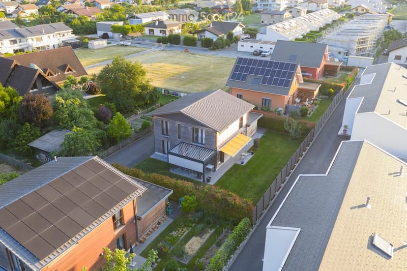 Aerial view of a residential neighborhood with multiple houses, solar panels, and well-maintained gardens.