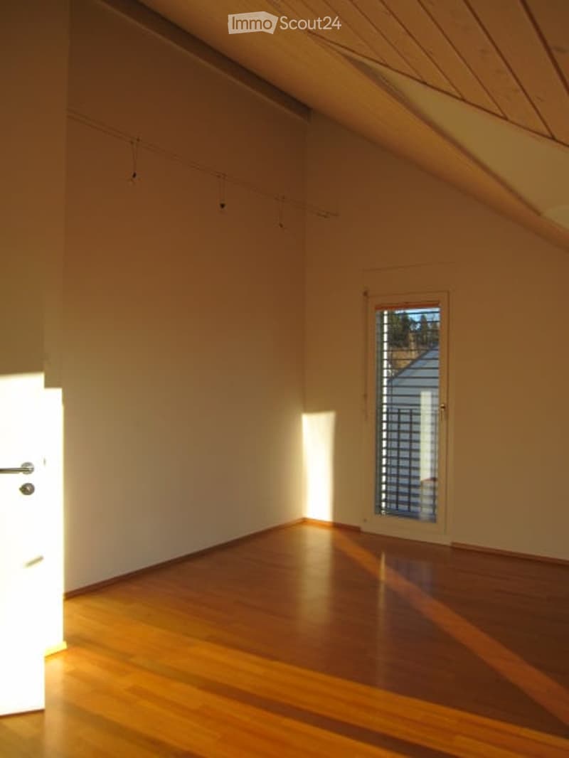 Empty room with wooden flooring, white walls, and a single window with a view of the outside.