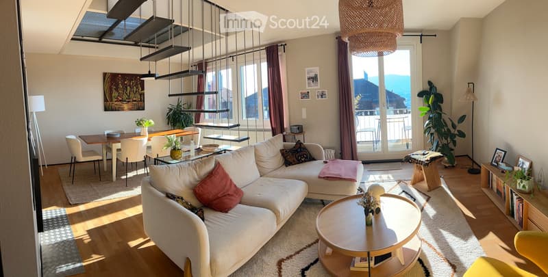 Bright living and dining area with modern furniture, large windows, and a view of the mountains.