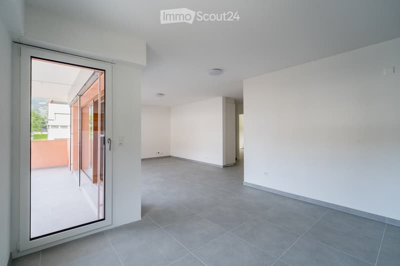 Empty room with grey tiled floor, white walls, and a large sliding glass door leading to an outdoor area.
