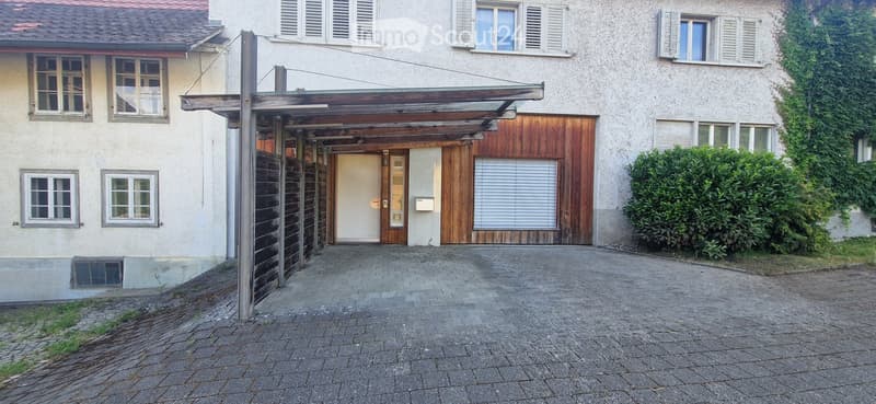 Two-story residential building with a covered entrance, garage, and multiple windows with shutters.