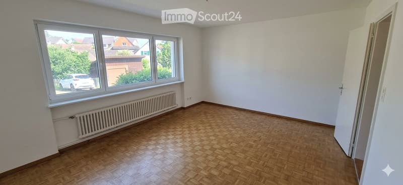 Empty room with wooden flooring, white walls, large windows, and a radiator. No furniture or equipment present.