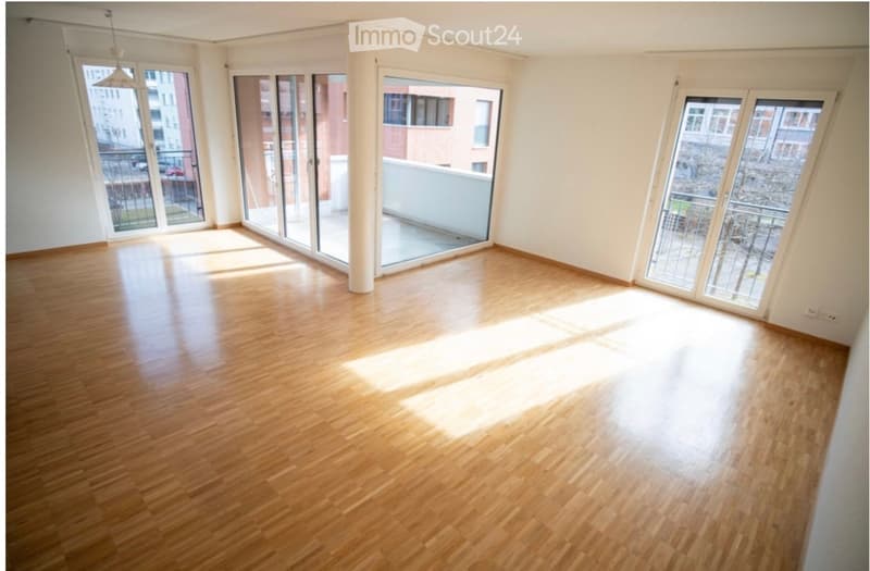 Empty room with wooden flooring and large glass doors leading to a balcony.