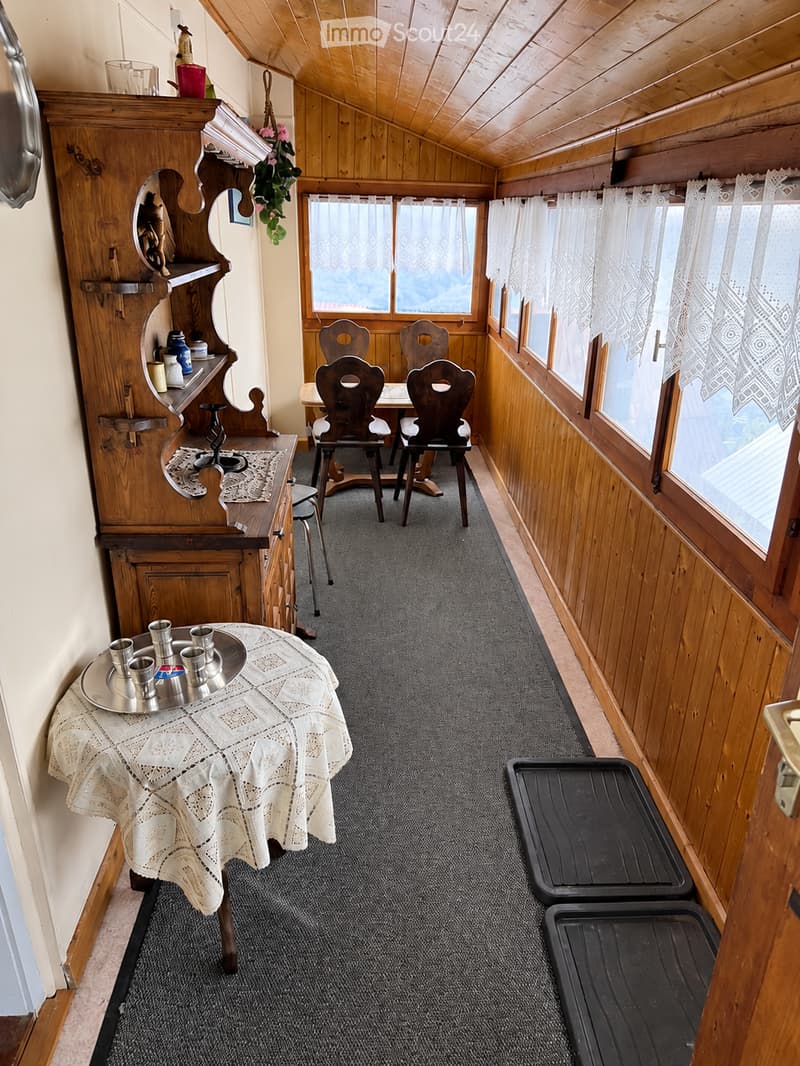 Cozy wooden-paneled room with a small dining area, featuring a table with chairs, a wooden cabinet, and a small table with cups and candles.