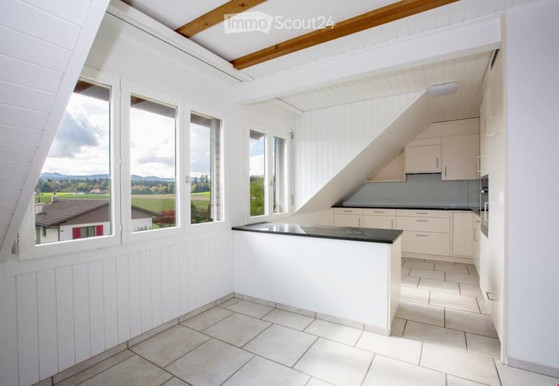 Bright, modern kitchen with white cabinets, a black countertop, and large windows offering a scenic view of the countryside.