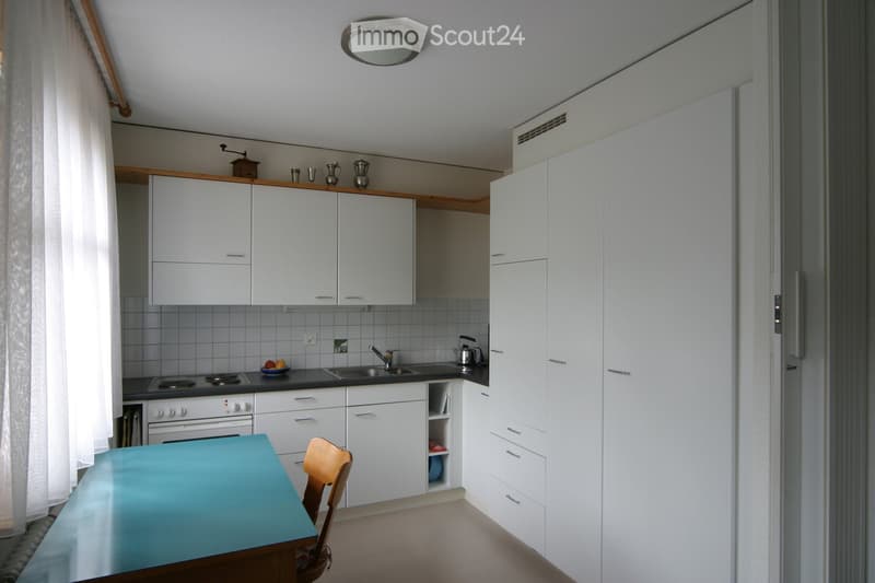 Modern kitchen, all white cabinets, tiled backsplash, gas stove, undermount sink, ceiling lamp, open shelving, and breakfast nook