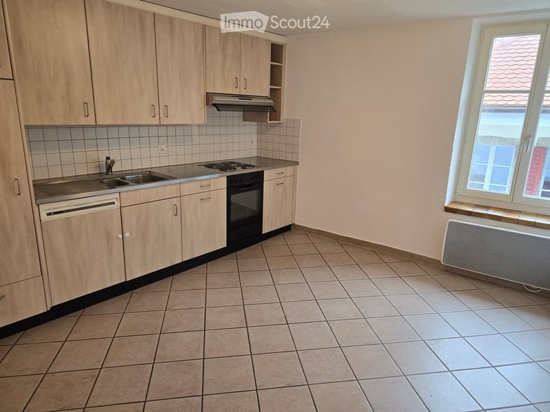 Empty kitchen with light wooden cabinets, tiled floor, sink, stove, oven, and dishwasher.