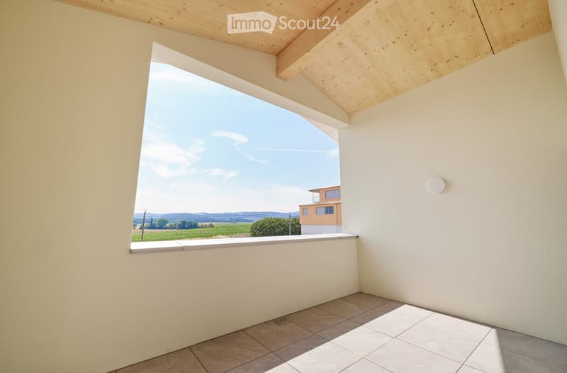 Balcony with wooden slatted ceiling, tiled floor, and expansive view of countryside and distant house.