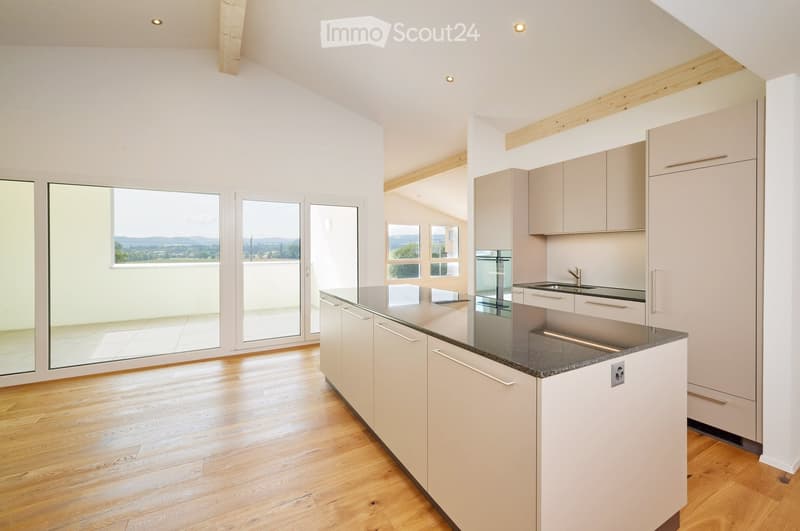Modern kitchen with light-colored cabinets, a central island, and large windows offering a scenic view.