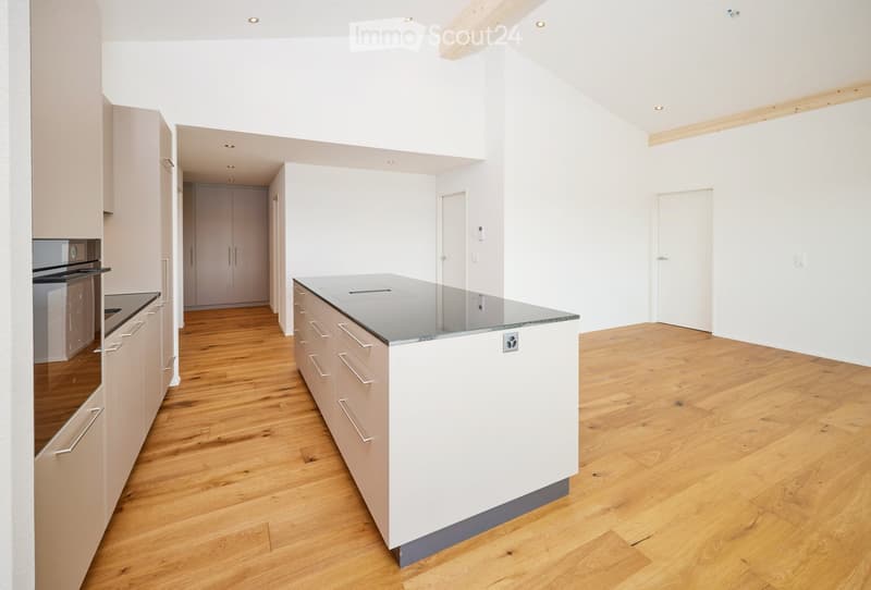 Modern kitchen with light-colored cabinets, a central island with a granite countertop, and wooden flooring.
