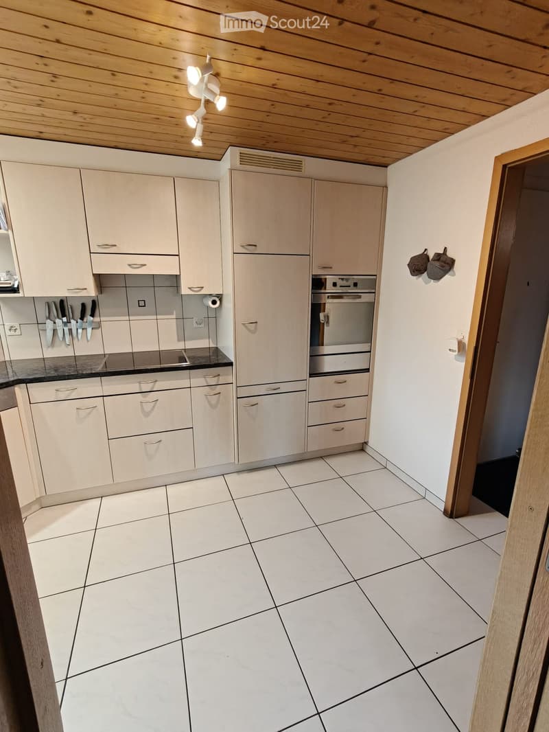 Modern kitchen with white cabinets, stainless steel oven, and tiled floor.