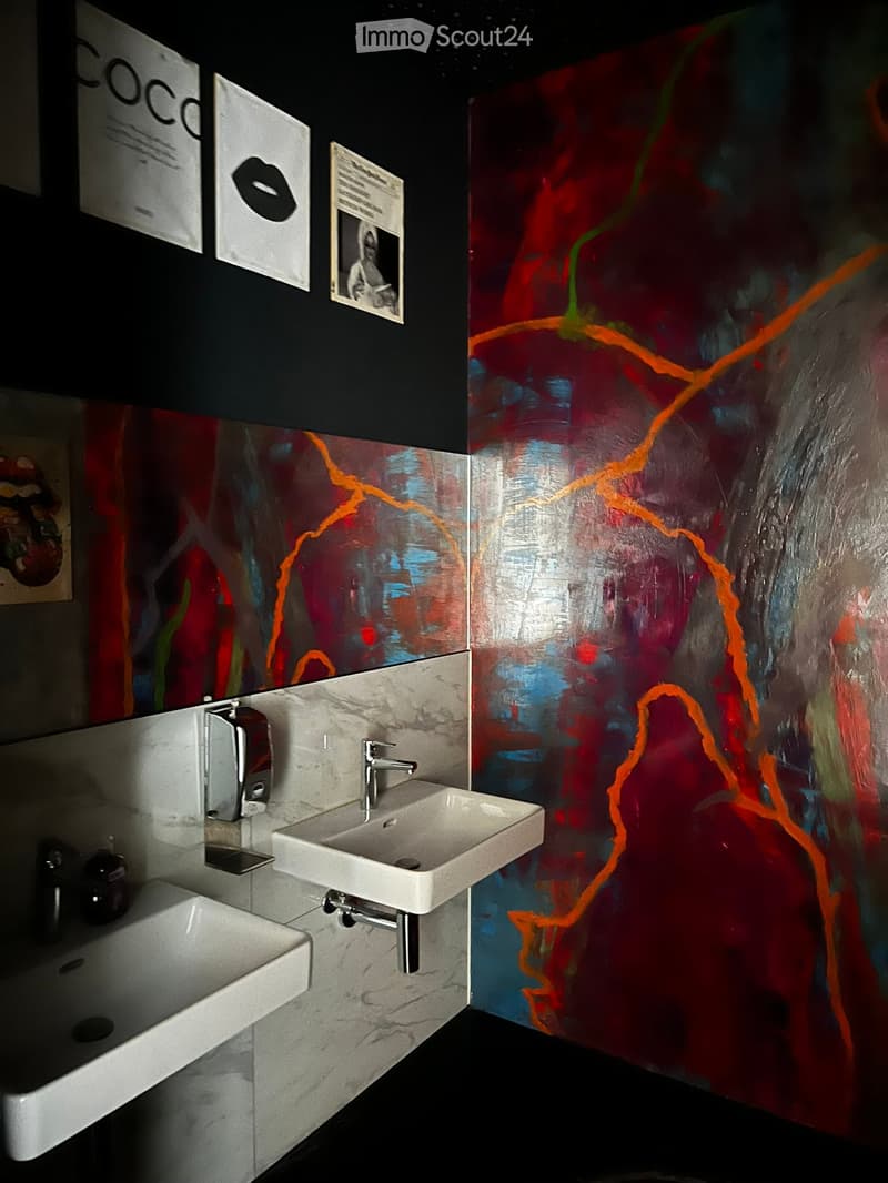 Modern bathroom with two white sinks, chrome faucets, and colorful abstract wall art.