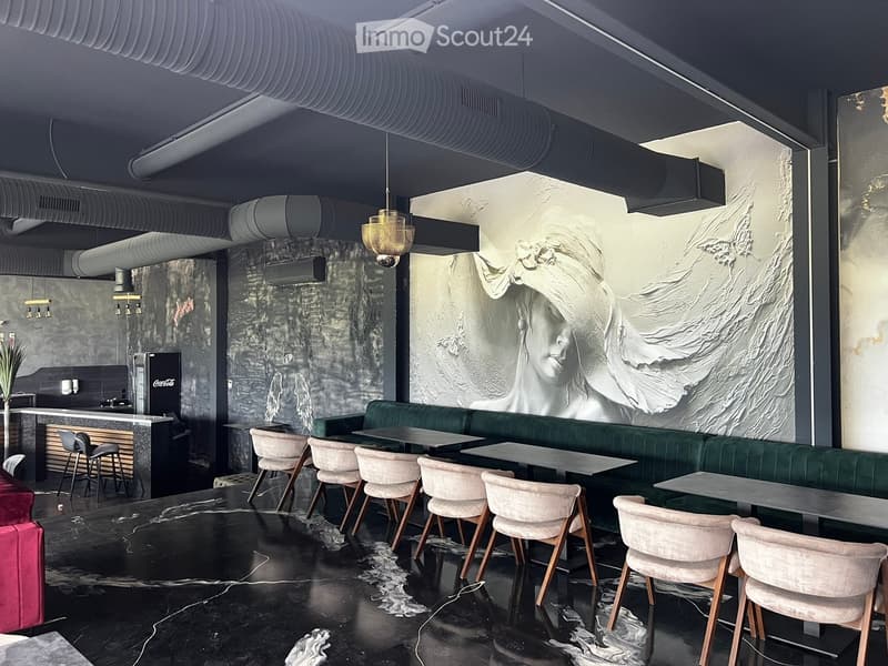 Modern restaurant interior with a large mural, green sofa, tables, chairs, and a bar area with stools.