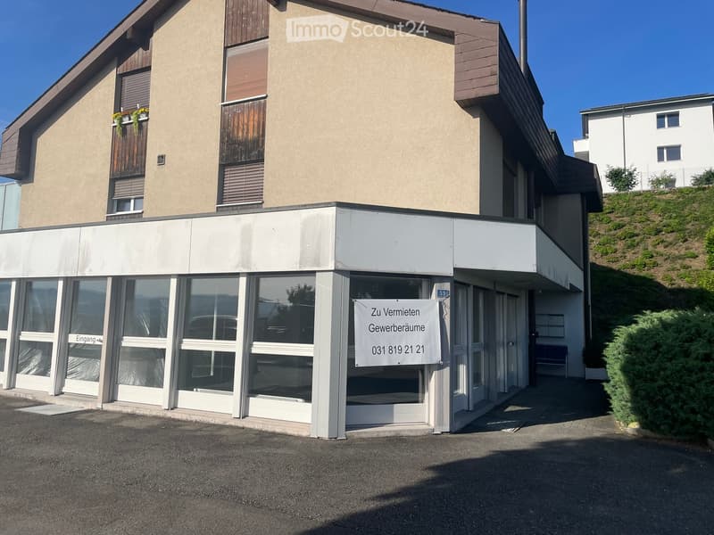 Two-story building with a modern facade, large windows, and a sign advertising commercial space for rent.