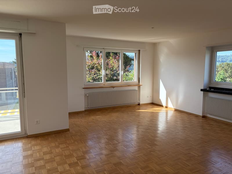 Empty room with wooden flooring, large windows, and radiators. No furniture or equipment present.