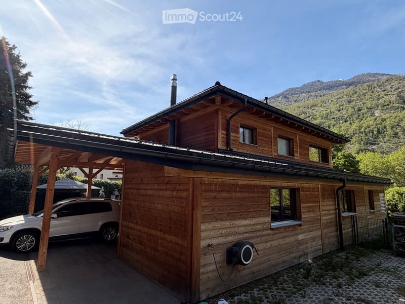 wooden exterior, car parked under carport, mountains in the background