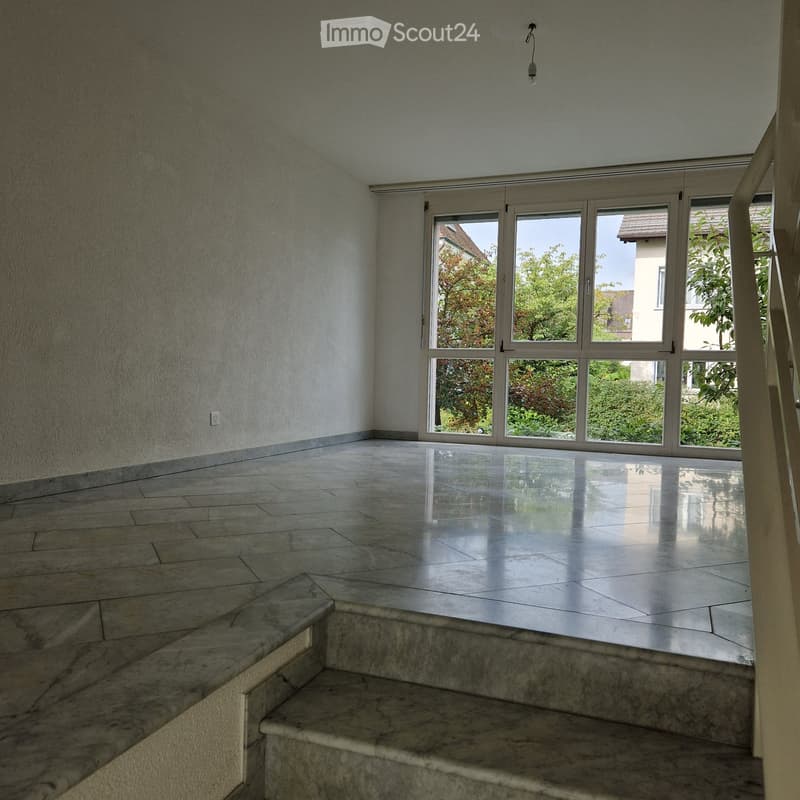 Empty room with polished tile flooring, large glass sliding doors, and a staircase leading upwards.