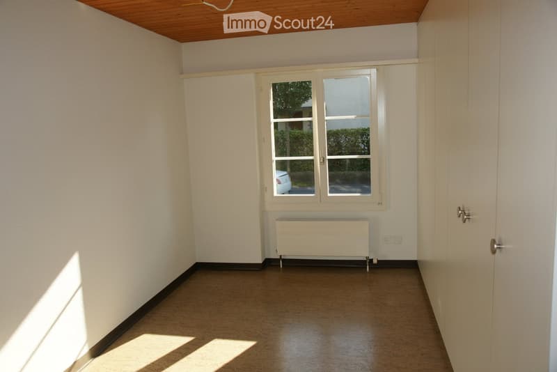 Empty room with white walls, wooden floor, and a window with a radiator below it. No furniture or equipment is present.