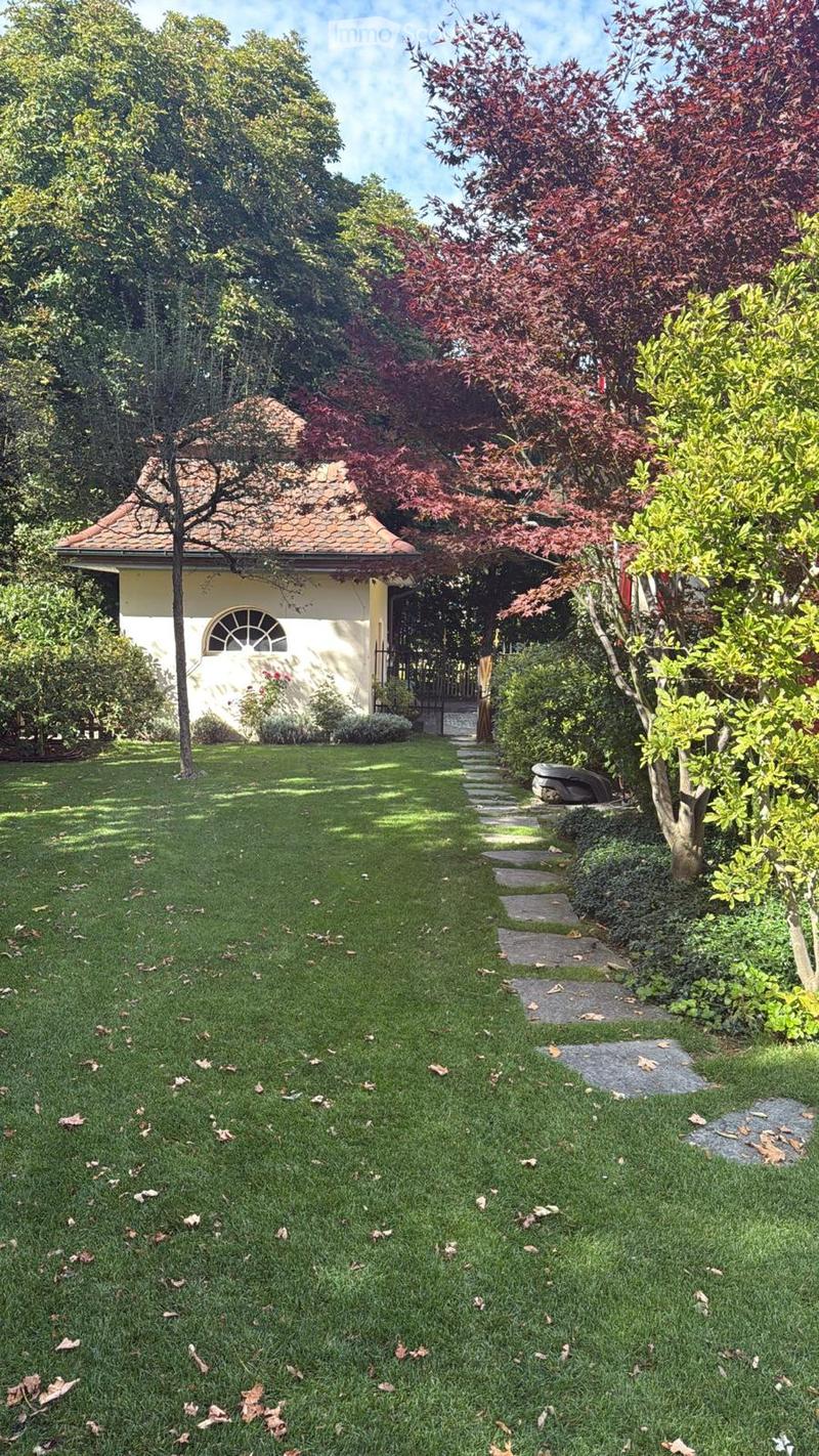 lush lawn, small house, gravel pathway, red leaves on trees, bushes and plants