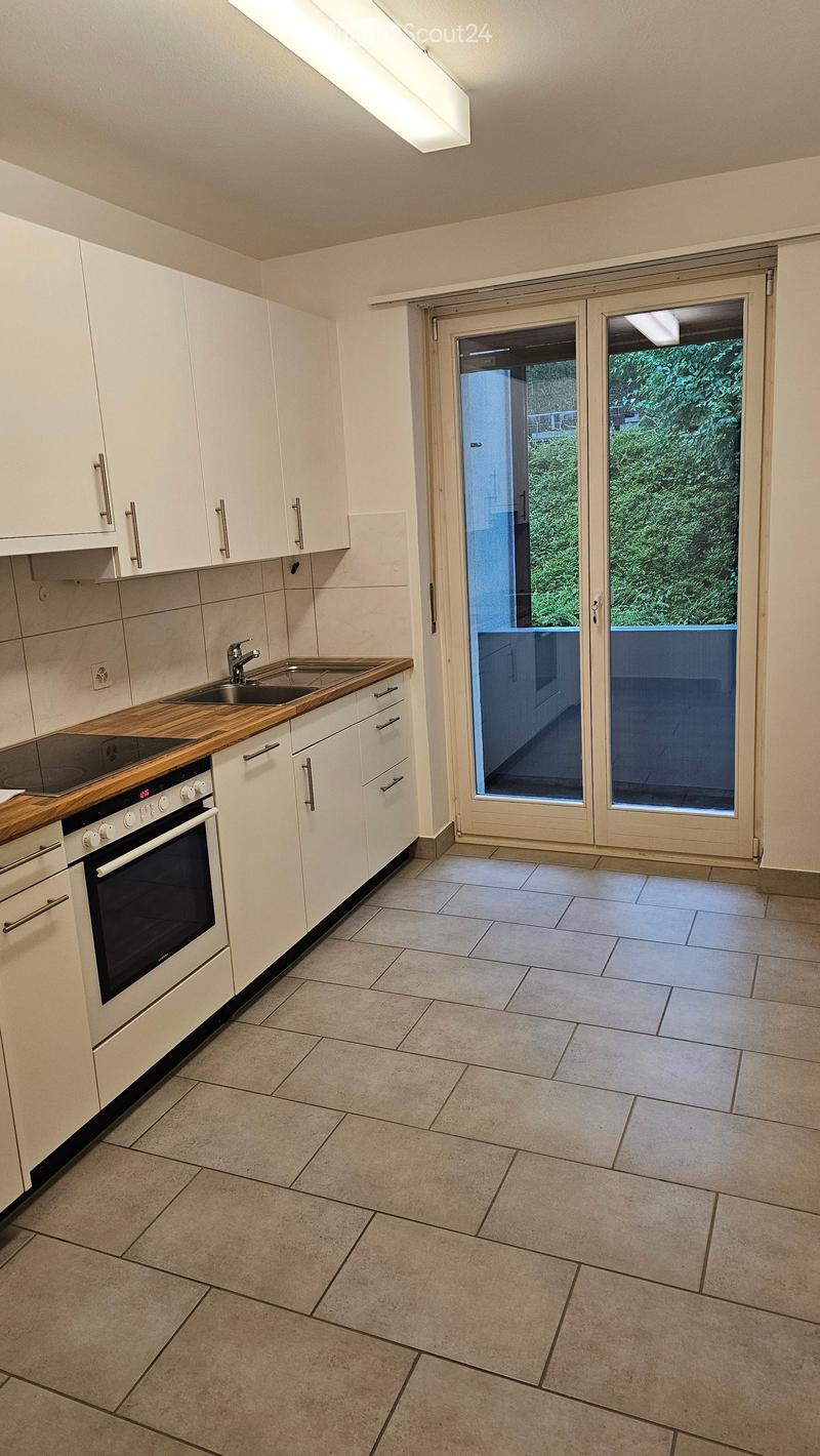 Modern kitchen with white cabinets, wooden countertop, built-in oven, and a large sliding glass door leading to a balcony.