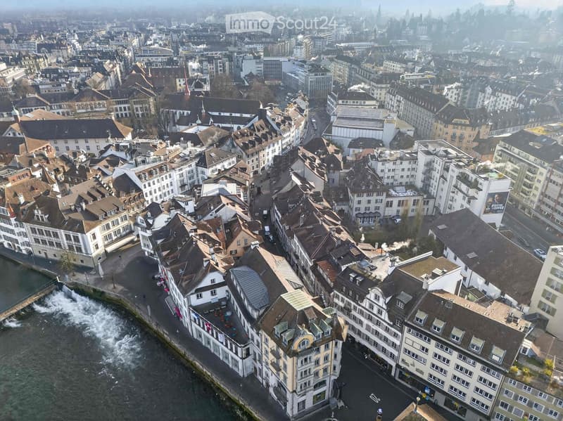 Aerial view of a dense urban area with numerous buildings, a river running through, and a mix of architectural styles.
