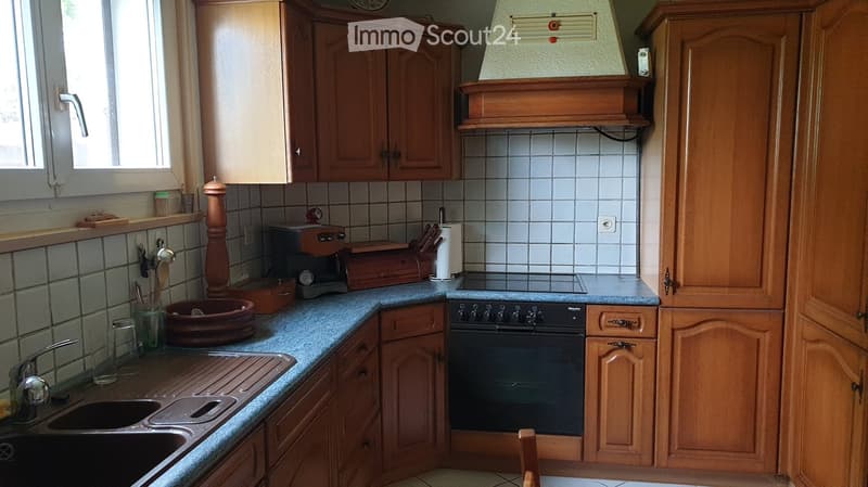 A well-equipped kitchen with wooden cabinets, a stainless steel sink, an oven, and various appliances and utensils neatly arranged on the countertops.