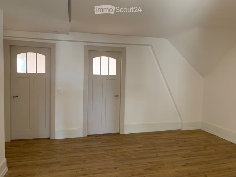 Empty room with wooden flooring, white walls, and two doors with glass panels.