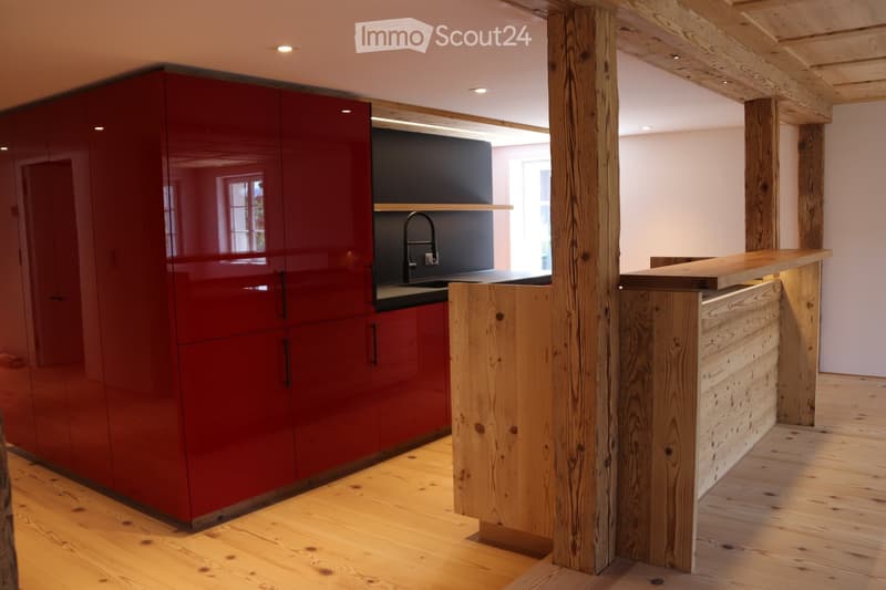 Modern kitchen with red cabinets, wooden island, and sleek sink area.