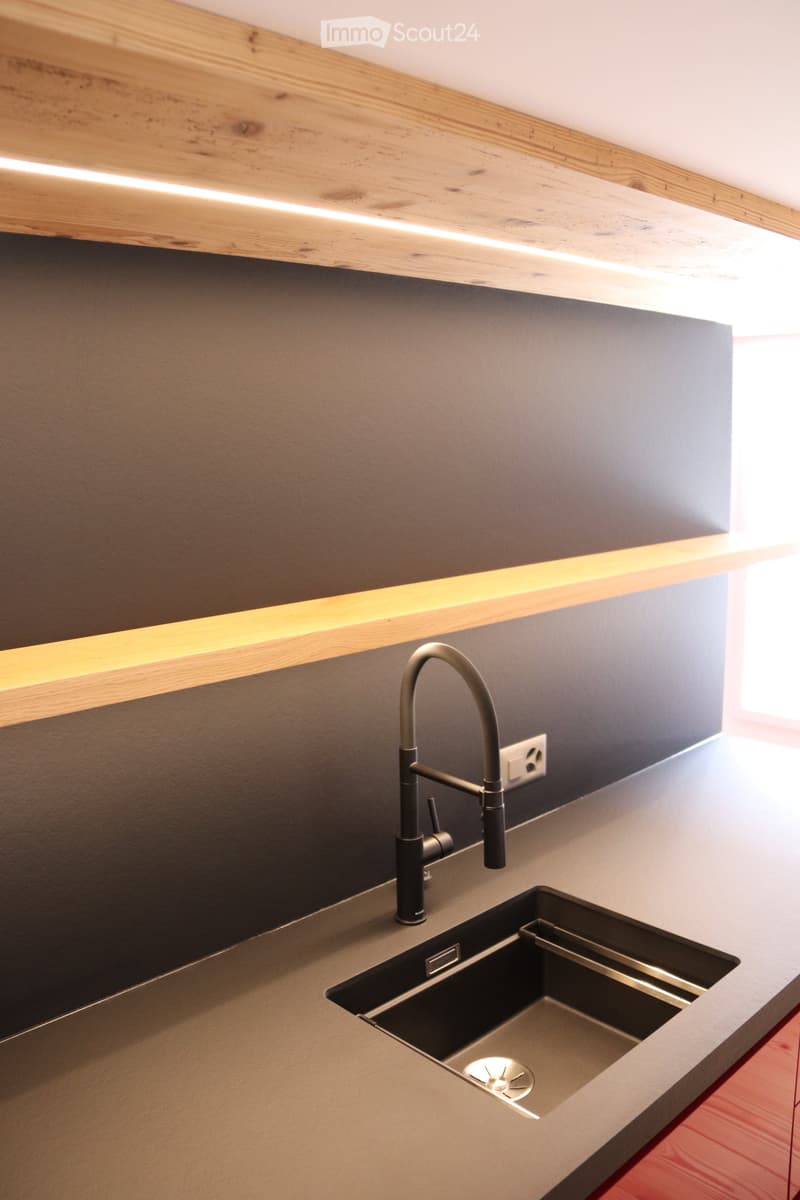 Modern kitchen sink area with a sleek, dark countertop, a contemporary faucet, and built-in LED lighting above.
