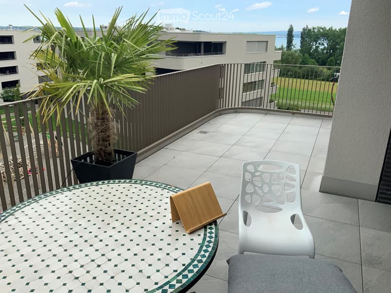 tiled floor, wooden table, white chair, view of surrounding buildings and greenery