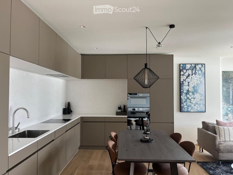 modern kitchen with wooden floor, white countertops, stainless steel appliances, pendant light, dining table, and a couch
