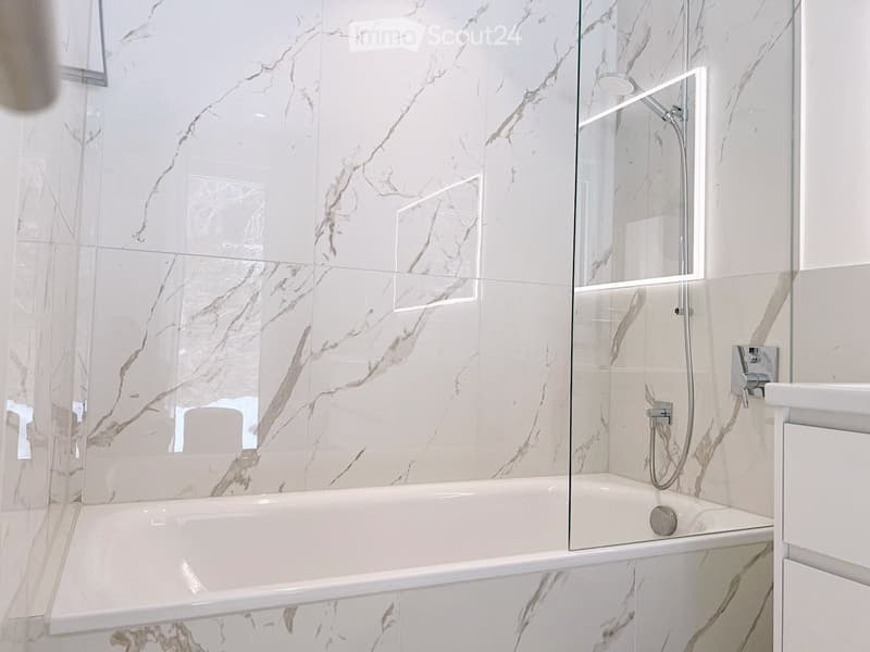 white marble tiles, glass shower enclosure, bathtub, shower head, faucet, white vanity
