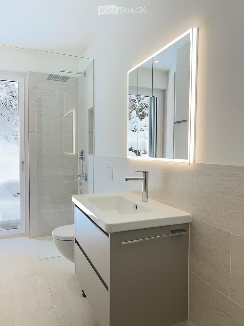 modern bathroom with white tiles, glass shower, white sink, mirror, toilet