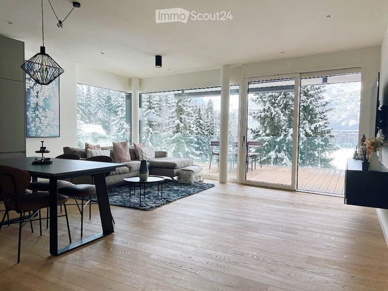 large windows, wooden floor, sofa, coffee table, rug, dining table, chairs, balcony, view of snowy mountains