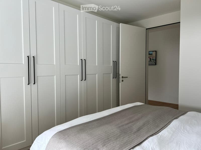Bedroom with a bed, white wardrobes, and a picture frame on the wall