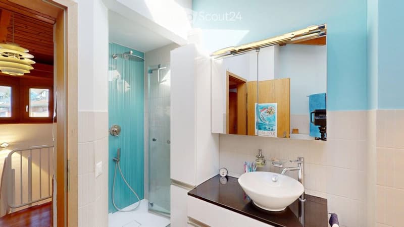 Modern bathroom with a white sink, mirror, glass shower enclosure, and wooden ceiling.