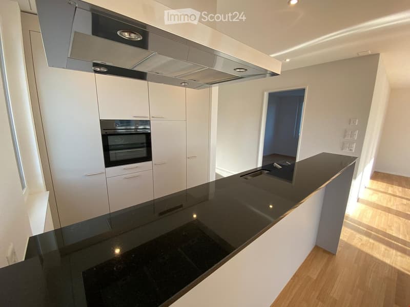 Modern kitchen with white cabinets, black countertop, and built-in oven. Features sleek design and ample storage space.