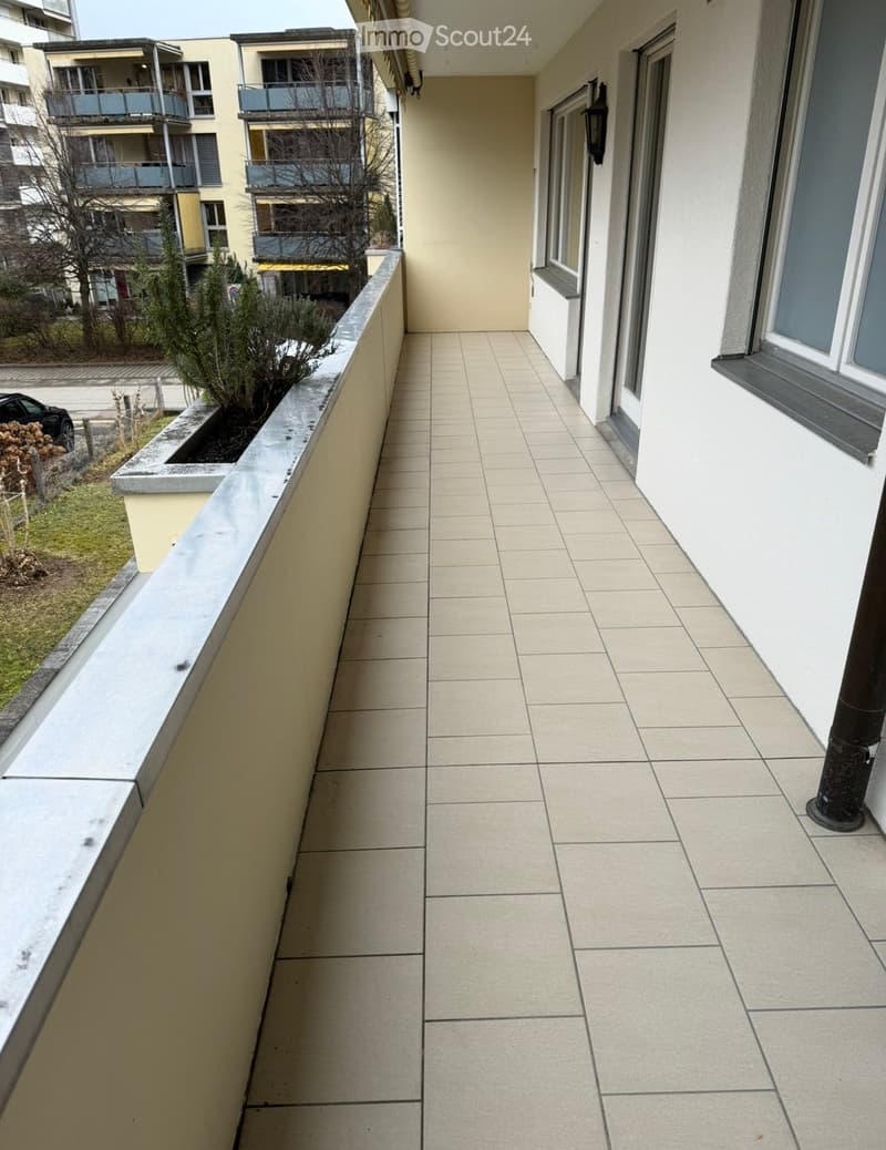 Balcony with tiled floor, beige walls, and a small planter on the left side.