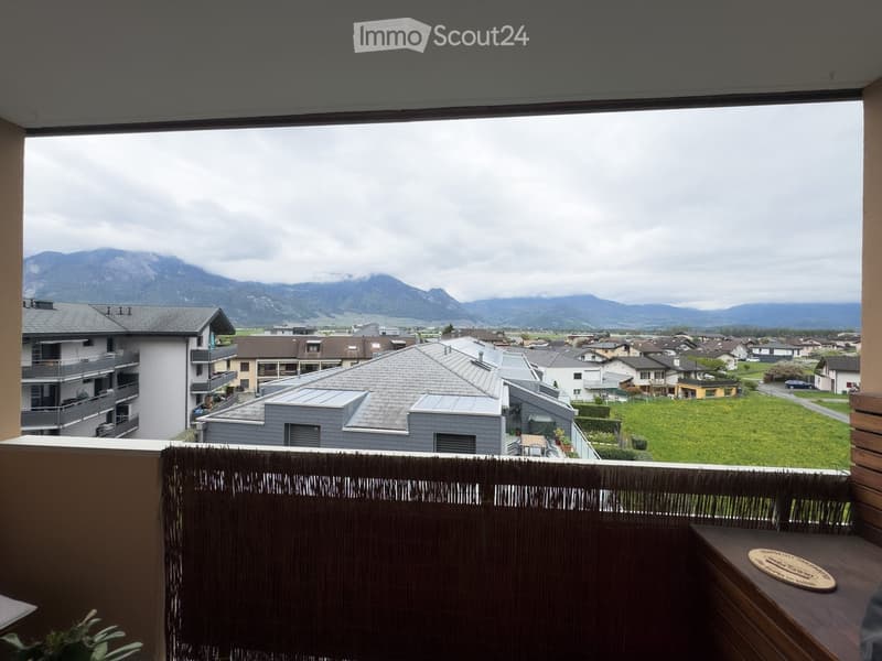 Balcony with a scenic mountain view, featuring a wooden railing and a small table with a circular wooden tray.
