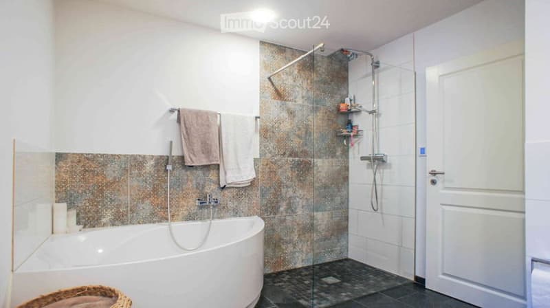 Modern bathroom with a freestanding bathtub, glass-enclosed shower, towel rack with towels, and a shower shelf holding toiletries.