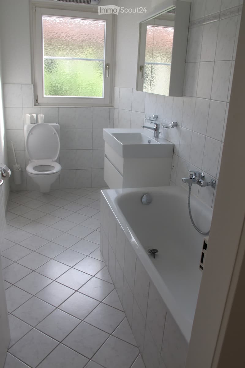 Bathroom with white tiles, toilet, sink, bathtub, mirror, and window