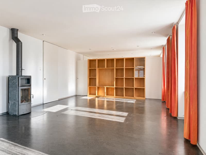 Modern, minimalist room with a polished concrete floor, white walls, a built-in wooden bookshelf, and a sleek black fireplace with a chimney.