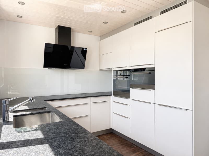 Modern kitchen with white cabinets, granite countertop, stainless steel sink and faucet, built-in oven, and range hood.