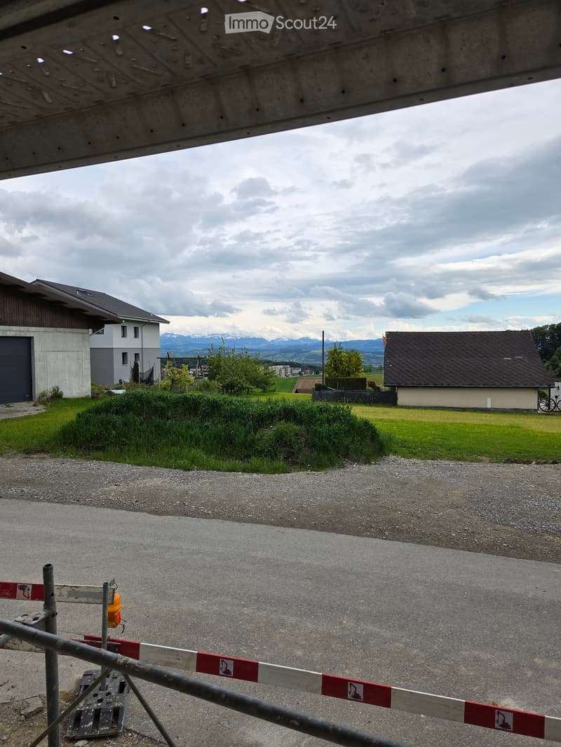 Residential area with houses, garage, and a gravel driveway under a cloudy sky.