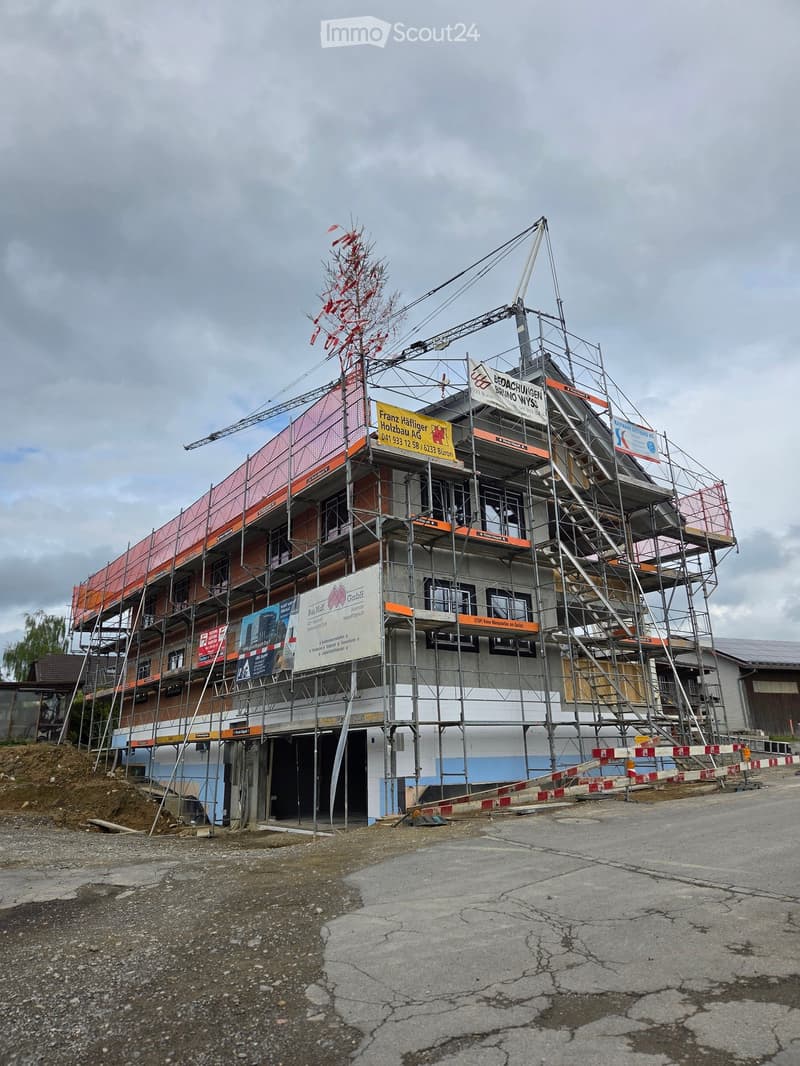 Multi-story building under construction with scaffolding, banners, and exposed structural elements.