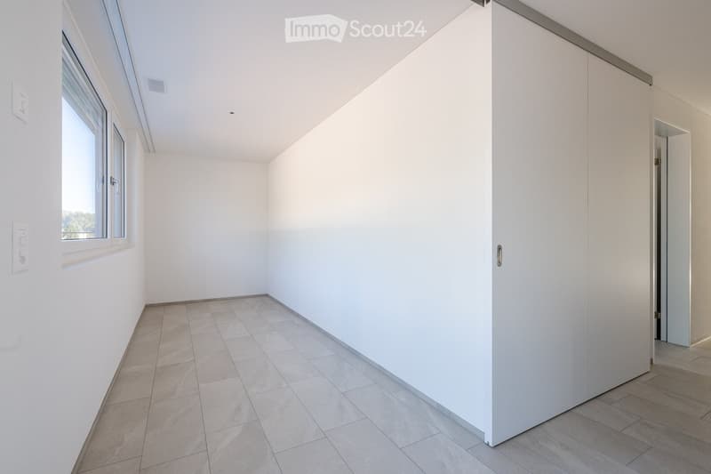 empty room, white walls, gray tile flooring, large window, built-in wardrobe