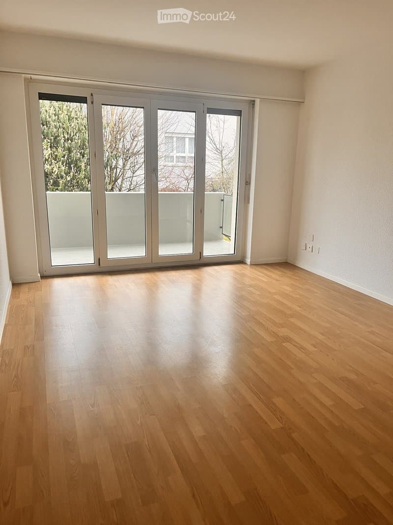 Empty room with wooden flooring and large sliding glass doors leading to a balcony.