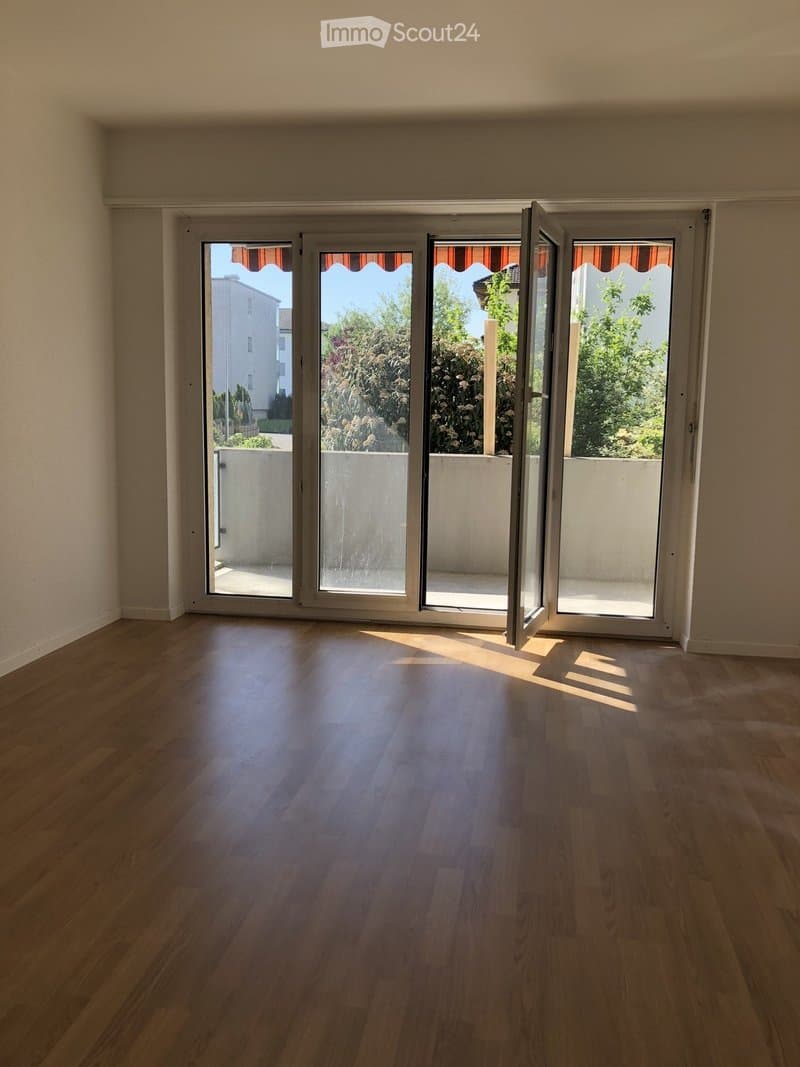 Empty room with wooden flooring and large sliding glass doors leading to a balcony or terrace.